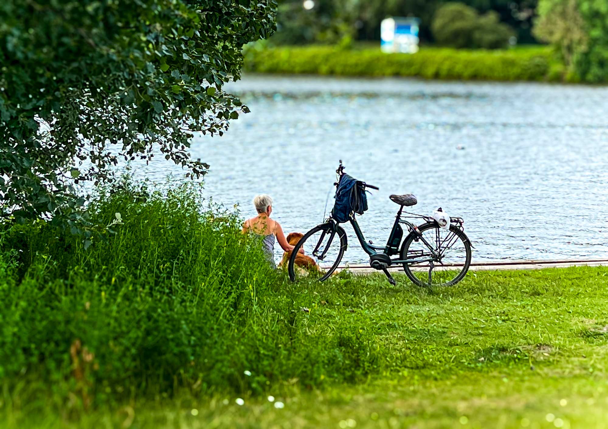 Frau mit Hund sitzend an der Weser.