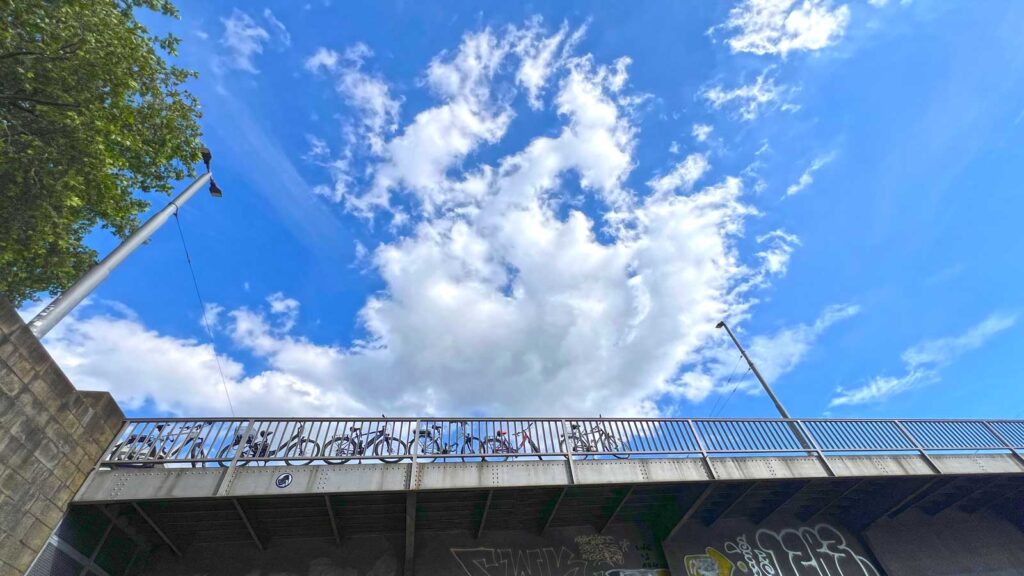 Blick auf die Wilhelm-Kaisen Brücke an der Schlachte in Bremen. Perspektive von unten. Oben sieht man dramatische Wolken und Fahrräder auf der Brücke.